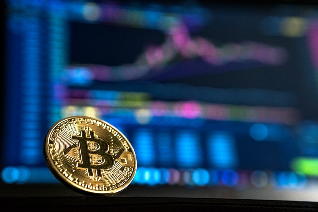 Cryptocurrency price chart on laptop beside Bitcoin coin