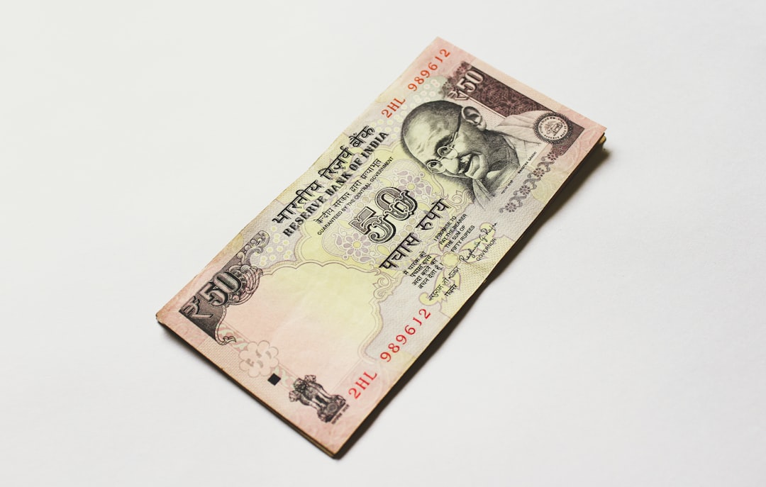 Indian rupee banknotes beside fuel pump nozzle